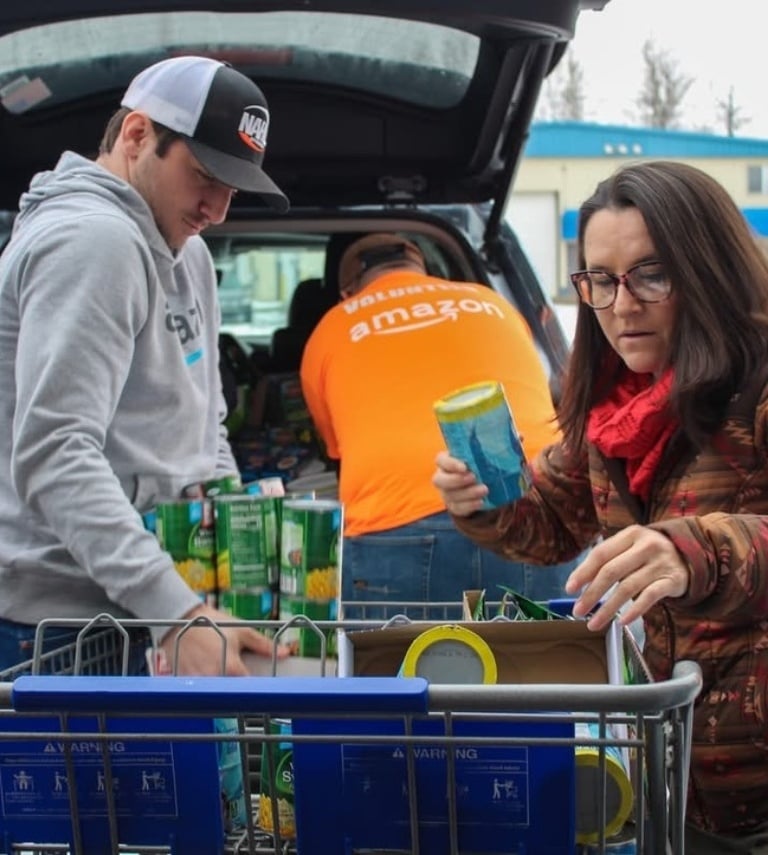 Amazon helping folks unload canned goods from the back of their vehicle