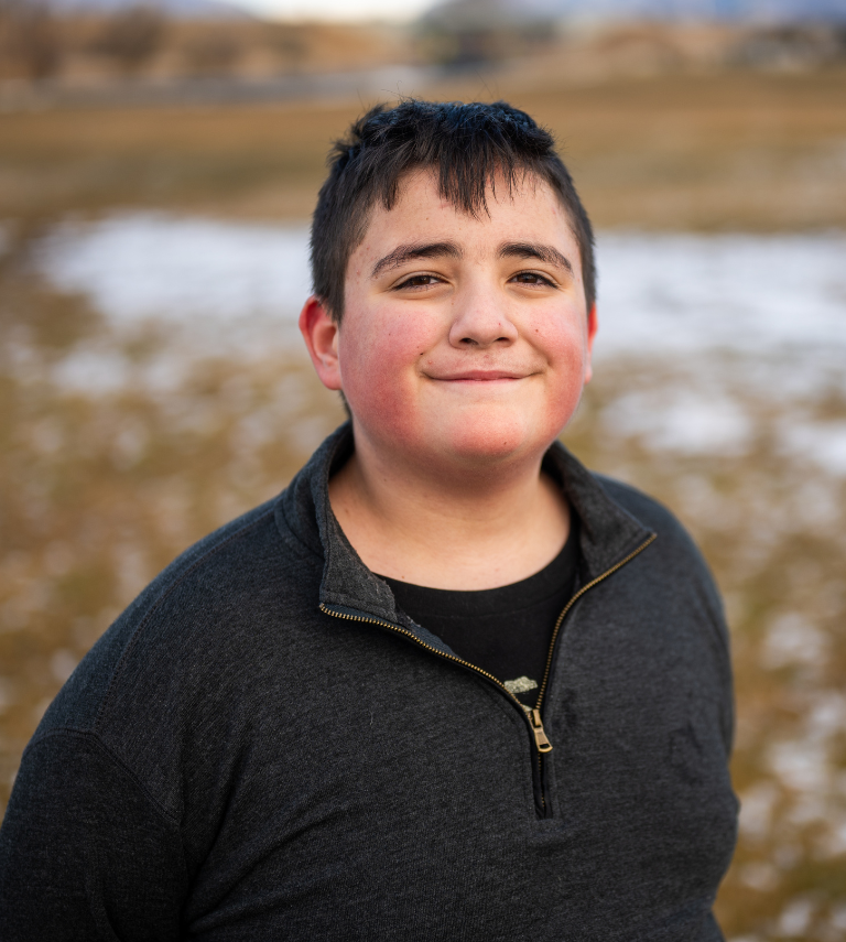 Young boy outside in the winter, looking up at camera