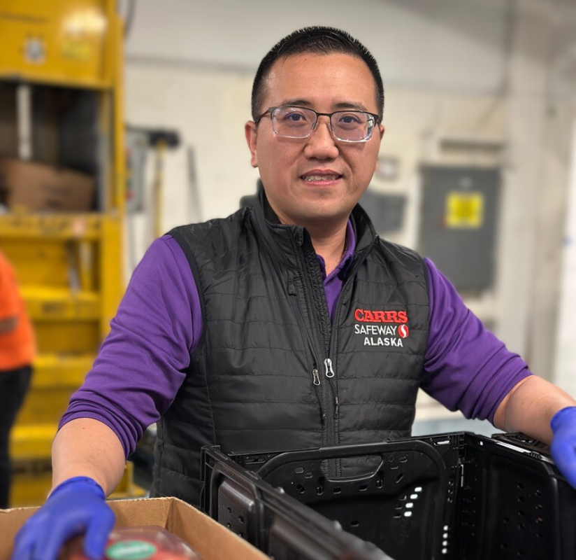 Man standing over fruit, smiling for the camera
